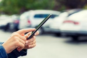 Woman uses her cell phone application connected to her car.